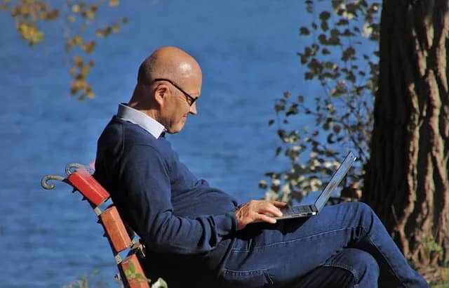 man with laptop, by water